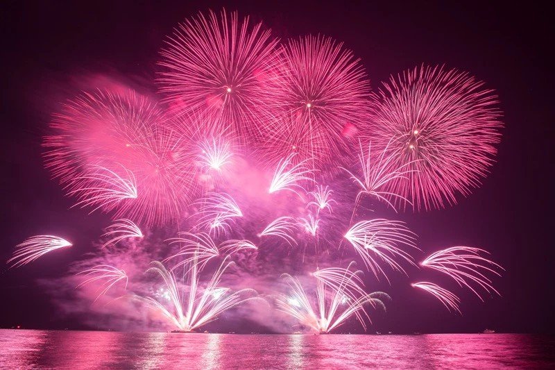 Fuochi d'artificio rosa e bianchi che si riflettono sull'acqua del lago a Como